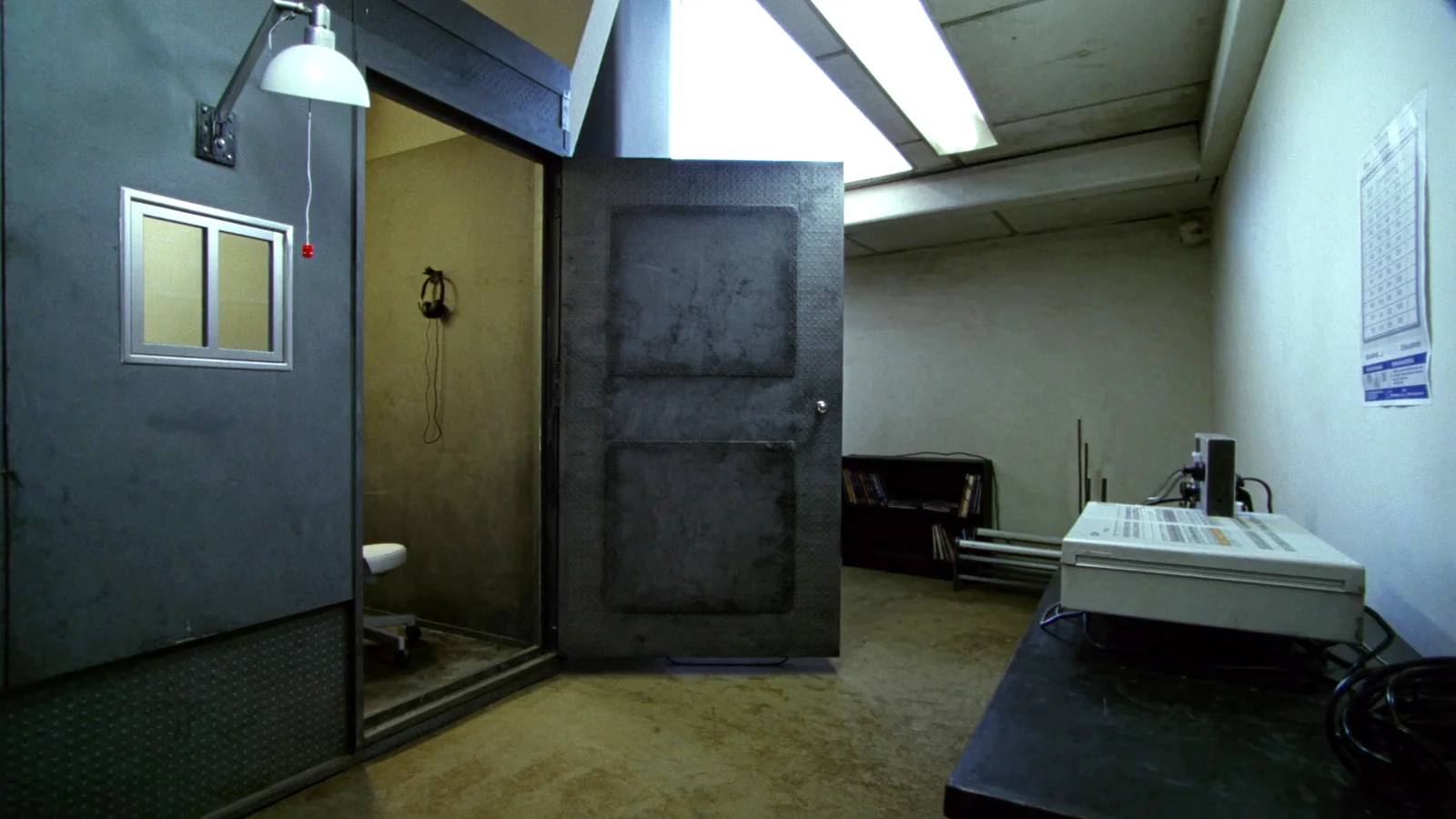 The open door of a double walled audiometric test booth in a small hearing office, a heavy steel box with a gasketed door and one small window.